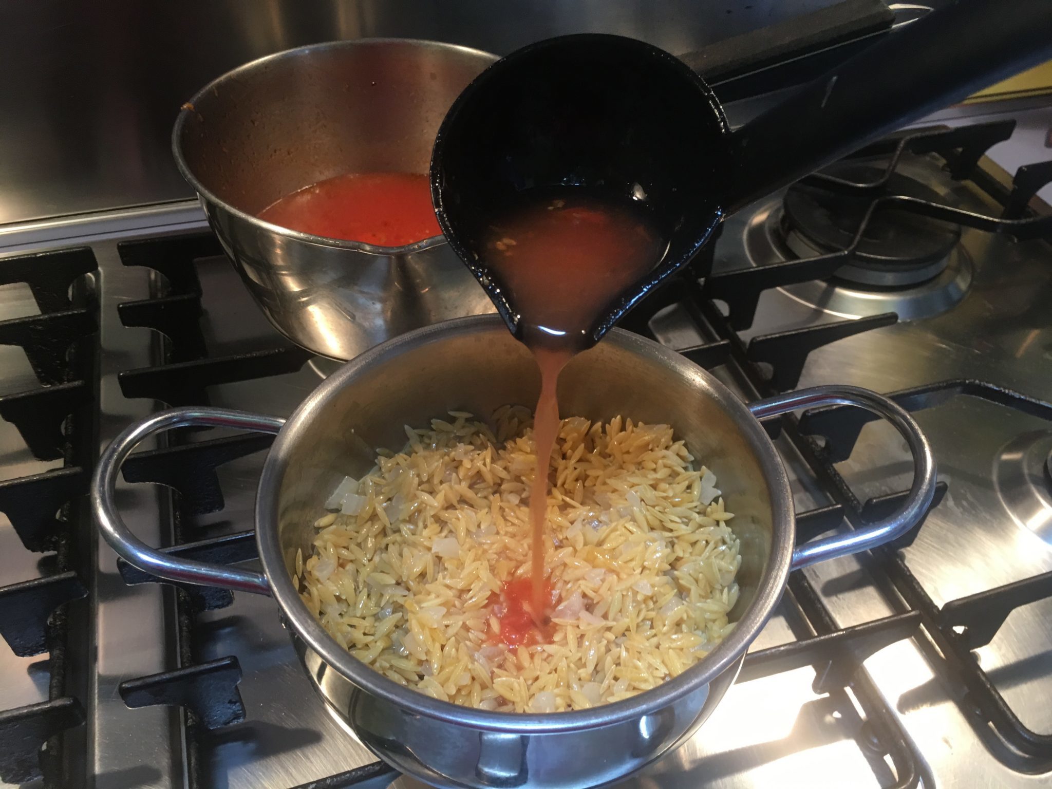 Risoni risottati - un mestolo di scolatura versato nella pasta